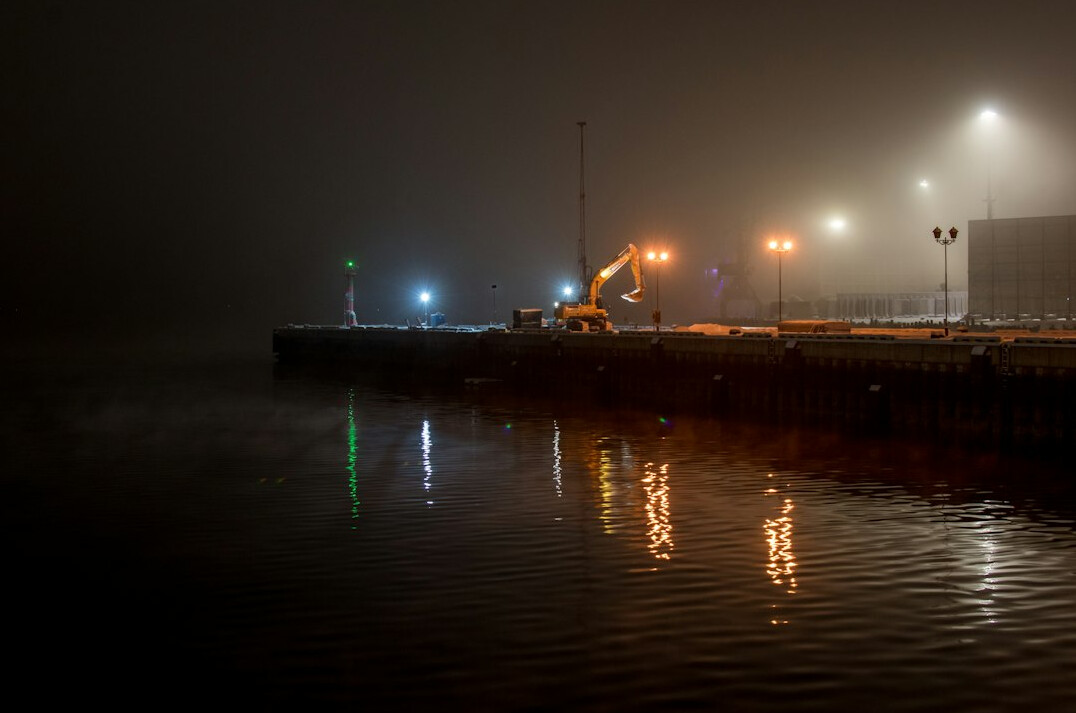 Foggy harbor at night with fishing boats and dim dock lights