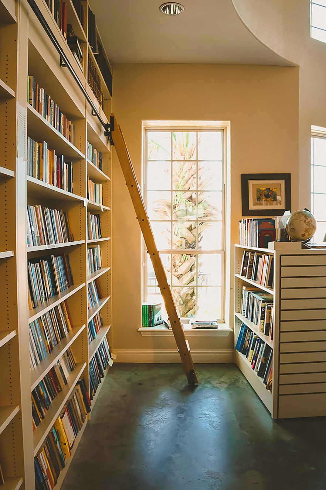 Tall wooden library shelves filled with old books and a rolling ladder