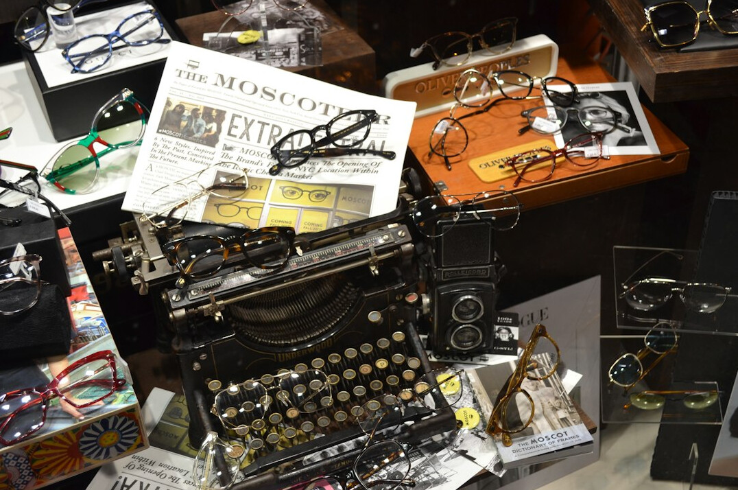 Vintage typewriter beside a magnifying glass and open notebook on a wooden desk